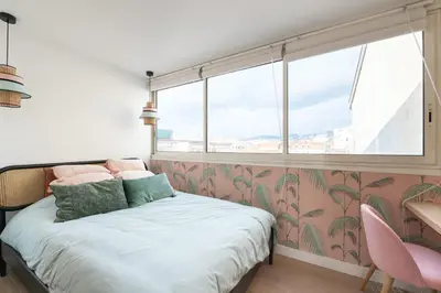 a bedroom with a bed and a window with pink wallpaper at Beautiful flat with terrace - Carre d'Or Cannes in Cannes