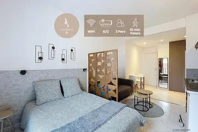 a bedroom with a blue bed and a kitchen at L'horloge I - Studio - 15 min Palais - Cannes in Cannes