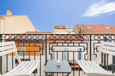 a table and chairs on a balcony with a building at L'horloge I - Studio - 15 min Palais - Cannes in Cannes