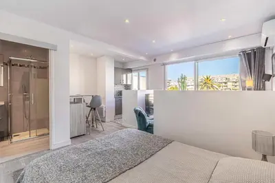 a bedroom with a bed and a large window at Magnificent studio with terrace - center of Cannes in Cannes