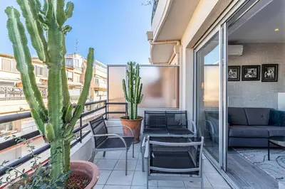 a balcony with a couch and chairs and a cactus at Magnificent studio with terrace - center of Cannes in Cannes