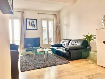 a living room with a black leather couch and a glass table at Appartements Cannes 3 chambres - 8B1 in Cannes