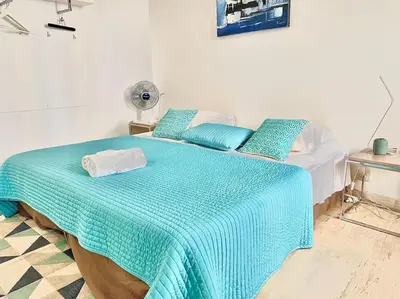 a bedroom with a bed with a blue blanket and a fan at Appartements Cannes 3 chambres - 8B1 in Cannes