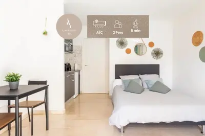 a bedroom with a bed and a table and a kitchen at L'Ariane - Studio - 5 min Plage - Climatisé in Cannes