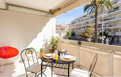 a balcony with a table and chairs and a view of a city at L'Ariane - Studio - 5 min Plage - Climatisé in Cannes