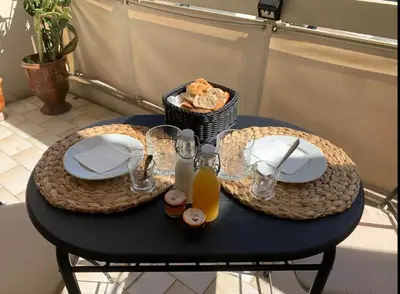 a table with two plates and a basket of food at L'Ariane - Studio - 5 min Plage - Climatisé in Cannes