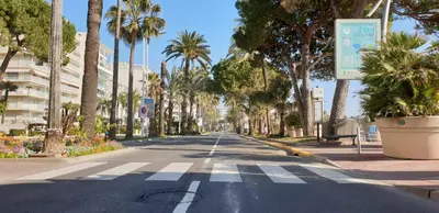 an empty street with palm trees and a building at Studio Croisette in Cannes