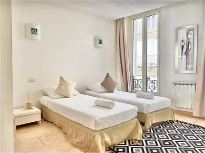 two beds in a white room with a window at Appartement Cannes 3 chambres - 8B2 in Cannes