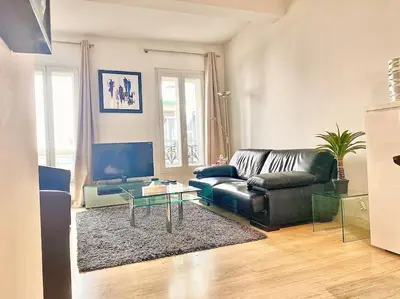 a living room with a black leather couch and a glass table at Appartement Cannes 6 chambres - 8B3 in Cannes