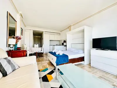 a bedroom with a bed and a couch and a tv at Le Splendide - studio croisette - vue mer in Cannes