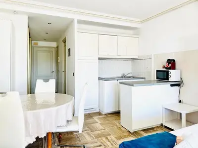 a kitchen with white cabinets and a table and chairs at Le Splendide - studio croisette - vue mer in Cannes