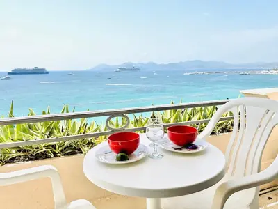 a white table with two cups and glasses on a balcony at Miramar - Studio Croisette - Vue Mer Panoramique in Cannes