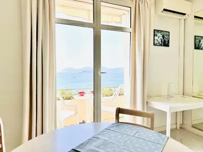 a room with a table and a view of the ocean at Miramar - Studio Croisette - Vue Mer Panoramique in Cannes