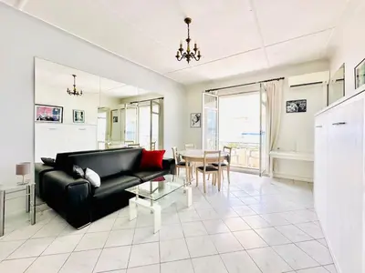 a living room with a black couch and a table at Miramar - Studio Croisette - Vue Mer Panoramique in Cannes
