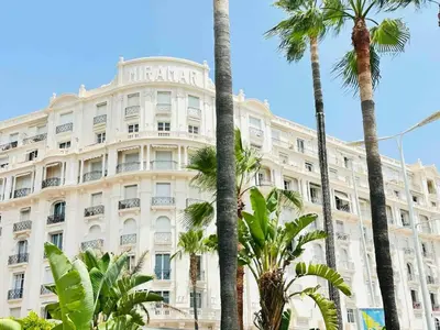 a large white building with palm trees in front of it at Le Belmondo - Studio Croisette - Palais Miramar in Cannes