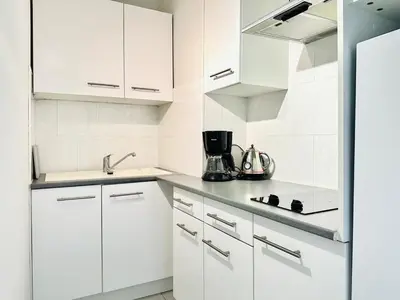 a white kitchen with white cabinets and a sink at Grand Hotel - Studio Croisette in Cannes