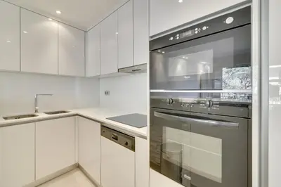 a kitchen with white cabinets and a stainless steel oven at Appartement calme et confortable -terrasse- Cannes in Cannes