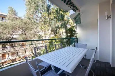 a balcony with a white picnic table and chairs at Appartement calme et confortable -terrasse- Cannes in Cannes