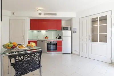 a kitchen with red cabinets and a table with fruit on it at Greg YourHostHelper in Cannes
