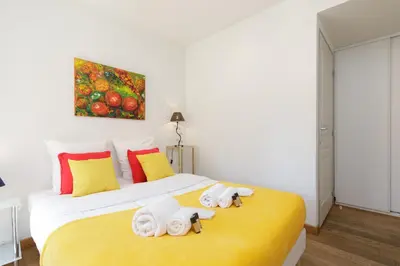 a bedroom with a yellow bed with towels on it at Greg YourHostHelper in Cannes
