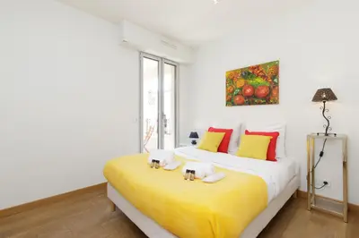 a bedroom with a large bed with yellow and red pillows at Greg YourHostHelper in Cannes