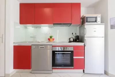 a kitchen with red cabinets and a white refrigerator at Greg YourHostHelper in Cannes