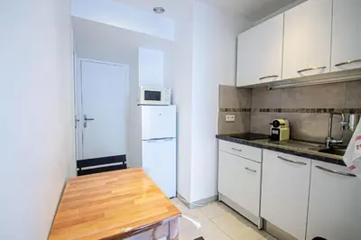 a kitchen with a white refrigerator and a wooden table at Lisa's Rooftop - Toit-terrasse à 2mn du Palais et des plages de la Croisette in Cannes