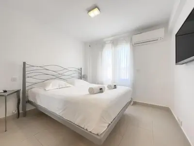 a white bedroom with a bed and a television at Le Maubourg by Winsome Destination in Cannes