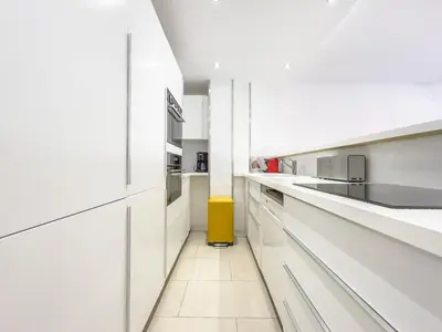 a kitchen with white cabinets and a yellow trash can at Le Maubourg by Winsome Destination in Cannes