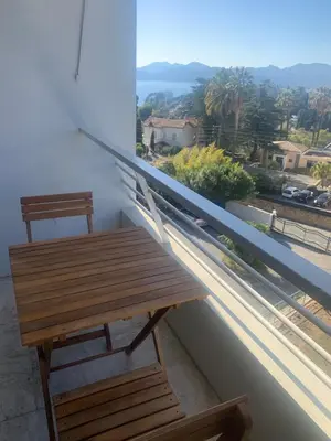 a wooden table and chair on a balcony with a view at Cannes vue mer in Cannes