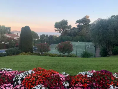 a park with flowers and a tennis court at Cannes vue mer in Cannes