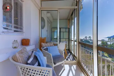 a balcony with a couch and chairs on a balcony at Lido Sea View, Congrès & Plage, clim, terrasse vue mer in Cannes