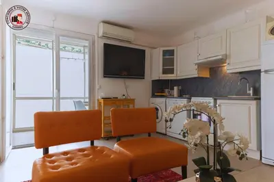 a kitchen with white cabinets and orange chairs in it at Lido Sea View, Congrès & Plage, clim, terrasse vue mer in Cannes