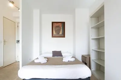 a bedroom with a bed with white walls and shelves at Studio with Huge Terrace close to the beach-Clim Mobile- BENAKEY in Cannes