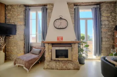 a living room with a fireplace and a clock on the wall at IMMOGROOM - T3 - Garden - Quiet - Air conditioning in Cannes