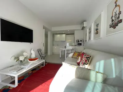 a living room with a white couch and a tv at Renovated Cannes Centre Banane balcon in Cannes