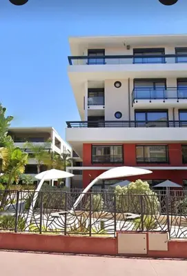 a building with tables and umbrellas in front of it at Appartement , piscine, terrasse, proche croisette in Cannes