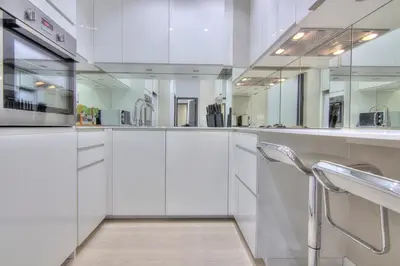 a large white kitchen with white cabinets and mirrors at Appartement Cannes 4 chambres - 5G in Cannes