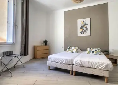 a bedroom with a bed and a chair in it at Appartement Canne 1 chambre - 21JOFFRE in Cannes