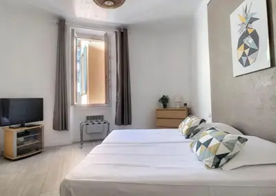 a bedroom with a large white bed and a television at Appartement Canne 1 chambre - 21JOFFRE in Cannes