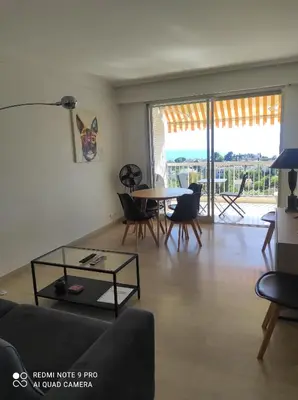 a living room with a table and chairs and a large window at superbe 2 pièces à Cannes vue imprenable in Cannes