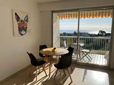 a dining room with a table and chairs and a balcony at superbe 2 pièces à Cannes vue imprenable in Cannes