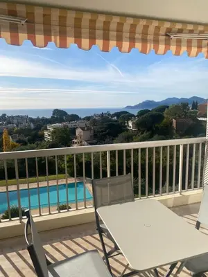 a table and chairs on a balcony with a pool at superbe 2 pièces à Cannes vue imprenable in Cannes