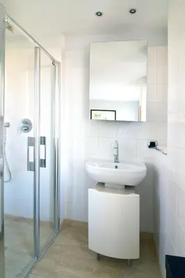a white bathroom with a sink and a shower at T3 vue mer LE MACE PLAGE in Cannes