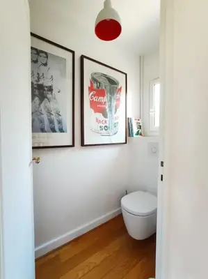 a bathroom with a toilet and two pictures on the wall at FRGK