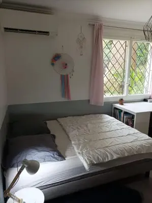 a bed in a bedroom with a lamp and two windows at FRGK