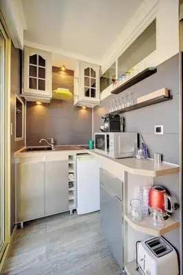 a small kitchen with white cabinets and a sink at Beautiful 28m2 studio with balcony in Cannes