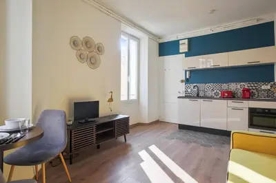 a kitchen with white cabinets and a desk with a computer at Studio Nid Doré - Welkeys in Cannes