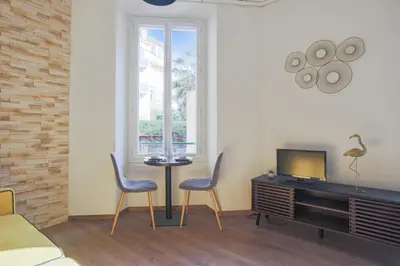 a living room with two chairs and a table and a tv at Studio Nid Doré - Welkeys in Cannes