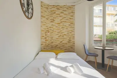 a bedroom with a bed and a clock on the wall at Studio Nid Doré - Welkeys in Cannes